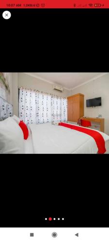 - une chambre avec un grand lit blanc aux accents rouges dans l'établissement Reddoorz near JIEXPO Kemayoran 2, à Jakarta