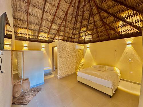 a bedroom with a bed and a straw roof at Awa de Mar Playa in Tolú