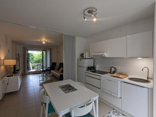 une cuisine avec des armoires blanches et une table dans une pièce dans l'établissement Arcachon centre, T2 de 47m², 200m plage, loggia, parking, idéal couple - FR-1-420-109, à Arcachon