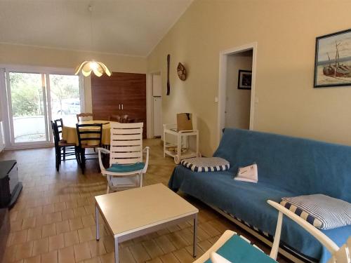 un salon avec un canapé bleu et une table dans l'établissement Charmant pavillon à Saint-Jean-de-Monts: 2 chambres, proche plage, forêt et commerces, jardin clos - FR-1-323-259, à Saint-Jean-de-Monts