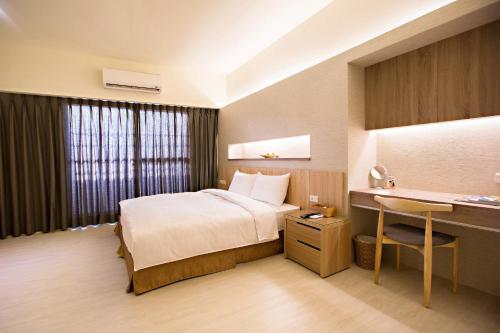 a hotel room with a bed and a desk at Traveller-Inn Zhongzheng Library in Taitung City