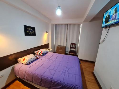 um quarto com uma cama roxa e uma televisão em Kallpa Wasi em Cusco