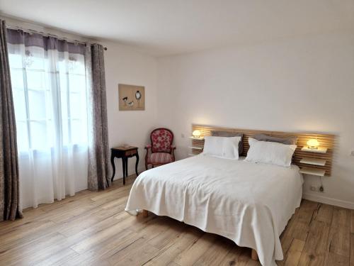 une chambre blanche avec un grand lit et une chaise dans l'établissement Villa avec Piscine à 15 min de La Rochelle, Proche Plages et Commerces - FR-1-706-13, à Angoulins-sur-Mer