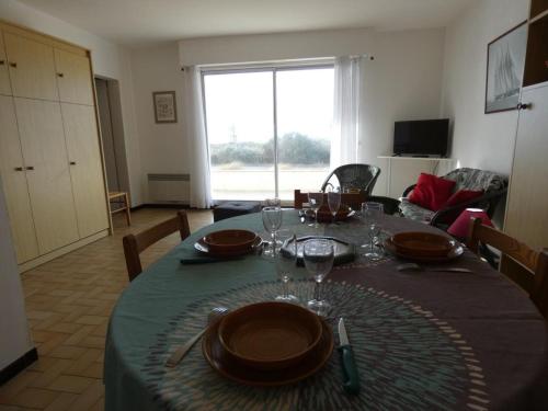 - une table à manger avec des assiettes et des verres à vin dans l'établissement Appartement bord de mer à Notre Dame de Monts - 38m², 4 pers, animaux admis - FR-1-540-250, à Notre-Dame-de-Monts