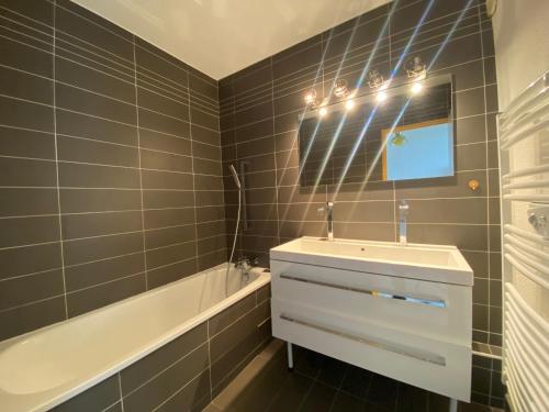 une salle de bain avec un lavabo, un miroir et une baignoire dans l'établissement Appartement T3 Front de Mer avec Terrasse, Parking et Accès Direct Plage au Moulleau - FR-1-374-212, à Arcachon