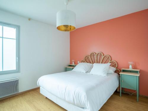 ein Schlafzimmer mit einer orangefarbenen Akzentwand und einem Bett in der Unterkunft Appartement Confort pour 4 au Centre de Mimizan – Plage, Lac, et Activités à Proximité - FR-1-50-119 in Mimizan