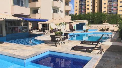 a pool with chairs and umbrellas next to a building at Cond. Mont Blanc Apto. 616 in Caldas Novas