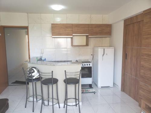 a kitchen with three bar stools and a refrigerator at Cond. Mont Blanc Apto. 616 in Caldas Novas