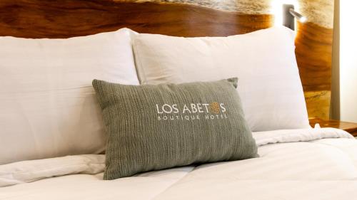 a pillow sitting on top of a bed with white pillows at Hotel Boutique Los Abetos in Boquete