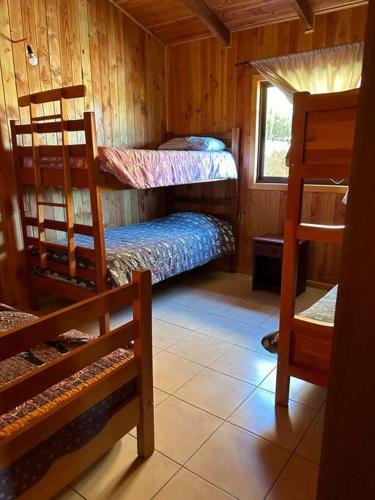 a room with two bunk beds and a window at Cabaña Flor de Lican in Licán Ray