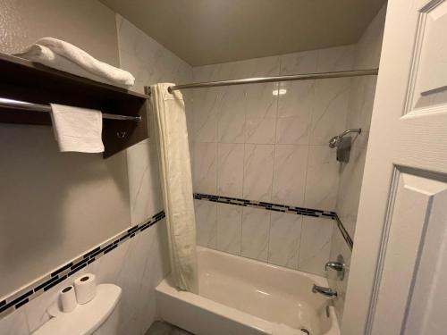 a bathroom with a shower and a tub and a toilet at SimpleStay Suites - Downtown San Bernardino in San Bernardino