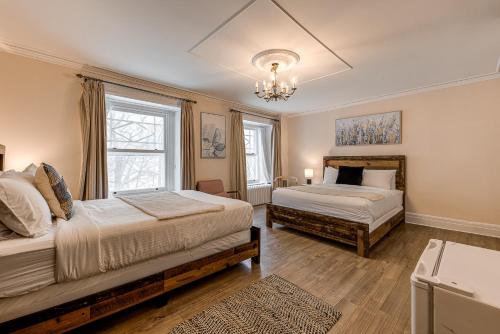 a bedroom with two beds and a chandelier at Auberge La Chouette in Quebec City