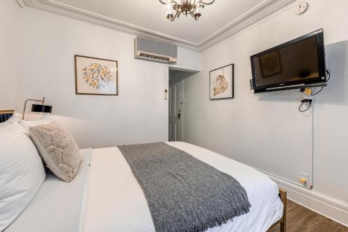 a bedroom with a bed and a flat screen tv at North House - Auberge La Chouette Hôtel Automatisé in Quebec City