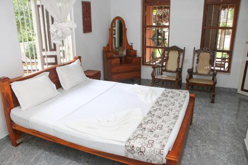 塔拉拉南的住宿－Gurugedara Heritage Talalla，一张位于带两把椅子和镜子的房间的床位