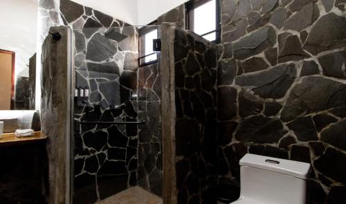 a bathroom with a toilet and a stone wall at Hotel Boutique Los Abetos in Boquete