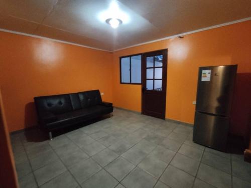 uma sala de estar com um sofá preto e um frigorífico em Departamento entrada privada em San Pedro de Atacama