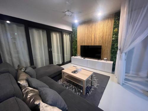 a living room with a large couch and a television at 4 Bedroom House with Beautiful Rooftop near BTS Ekkamai in Bangkok