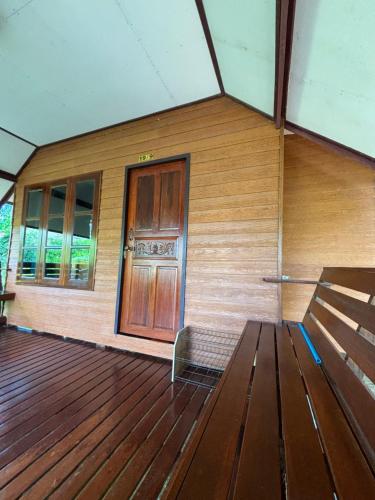 a wooden building with a wooden door and a bench at Baan Ja Da in Ban Nai Khlong