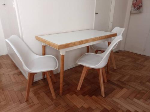 une table en bois entourée de deux chaises blanches dans l'établissement Confortable departamento en Retiro, à Buenos Aires