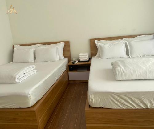 two beds in a hotel room with white pillows at HA PLEIKU in Pleiku