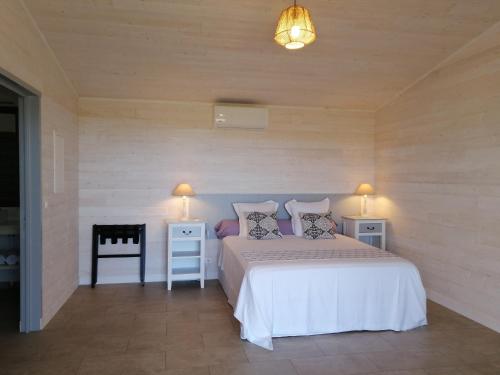 a bedroom with a bed with two tables and two lamps at NIAOULI LODGE in Bourail