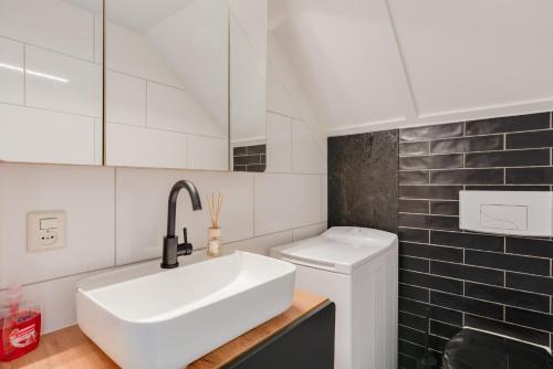 Baño blanco con lavabo y aseo en Het Huys Ewijk mooi luxe en een laadpaal, en Ewijk