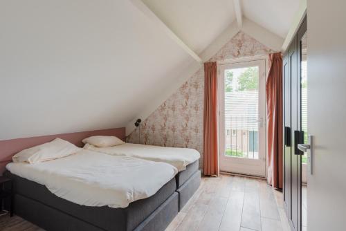 een slaapkamer met 2 bedden en een raam bij Het Huys Ewijk mooi luxe en een laadpaal in Ewijk