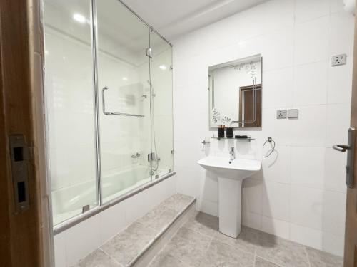 ein weißes Bad mit einem Waschbecken und einer Dusche in der Unterkunft The AUD Luxury Apartments in Kumasi