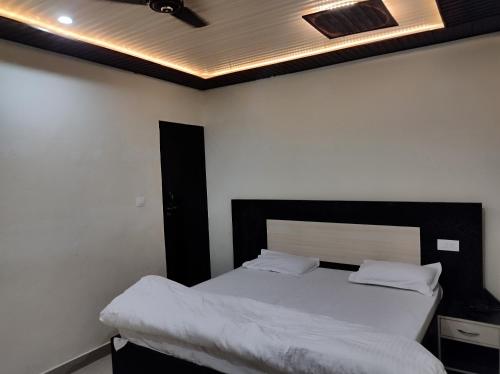 a bedroom with a bed with white sheets and a ceiling at Arvind Conference Halls in Jhānsi