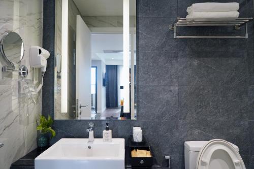 een badkamer met een wastafel, een toilet en een spiegel bij Armin Homes Altara Residences Quy Nhon in Quy Nhon