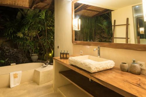 a bathroom with a sink and a tub and a mirror at Sunset Beach Villa Zanzibar 