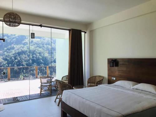 a bedroom with a bed and a large glass window at Mandara Mount Hotel in Ella
