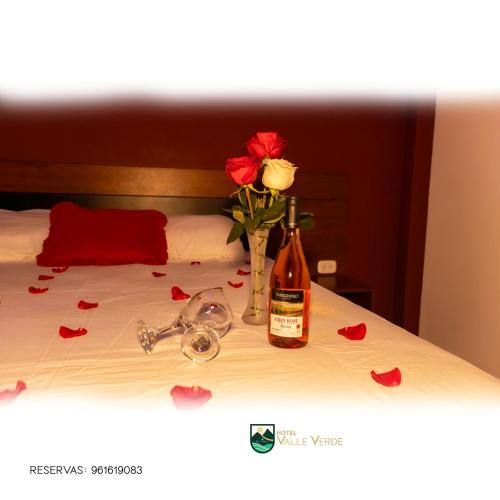 eine Flasche Wein und eine Vase mit Rosen auf dem Bett in der Unterkunft Hotel Valle Verde in Cajamarca