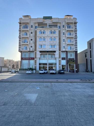 um grande edifício com carros estacionados em frente em بيت السلطانة للأجنحة الفندقية em Salalah