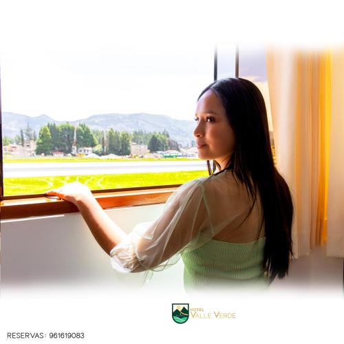 a woman is looking out of a window at Hotel Valle Verde in Cajamarca