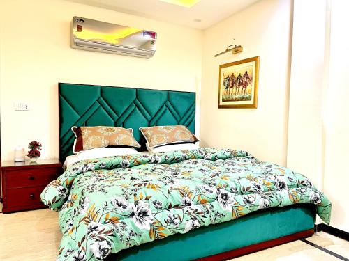 a bedroom with a large bed with a green headboard at National Luxury Apartments DHA - 3 BedRoom opposite Airport in Lahore