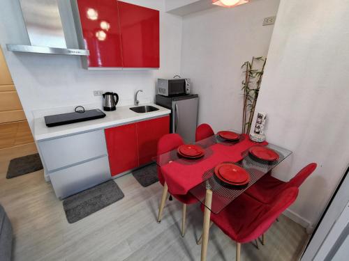 a small kitchen with a red table and red chairs at Cozy Apartment with Lagoon View in Manila