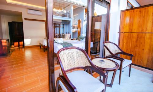 a room with chairs and a bed and a table at Relaxful Hotel泊岸酒店 in Luang Prabang