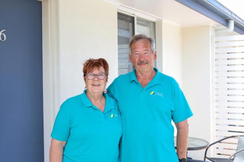 een man en vrouw in blauwe shirts poserend voor een foto bij Robetown Motor Inn & Apartments in Robe