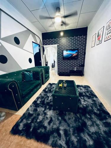 a living room with a green couch and a black rug at Kuu Inn Homestay Tmn Sri Wang Fasa 2 in Arau
