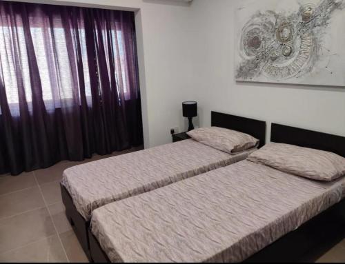 two twin beds in a room with a window at 4 bedroom apt 5 mins away from beach and amenities in St Paul's Bay