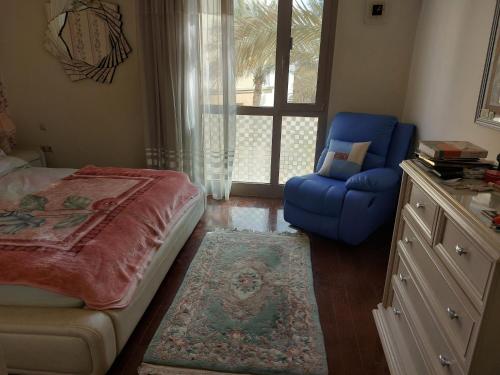 a bedroom with a bed and a blue chair and a window at In the heart of Cairo in Cairo