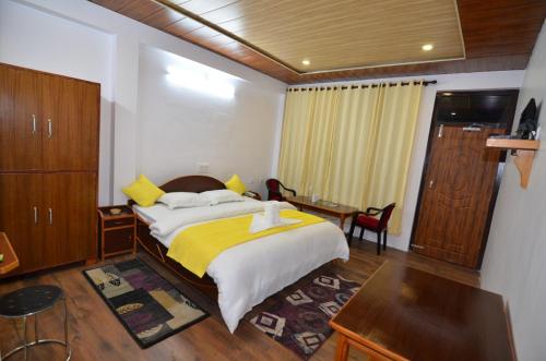 ein Schlafzimmer mit einem großen Bett und einer gelben Decke in der Unterkunft Hotel Milam Inn in Munsyari