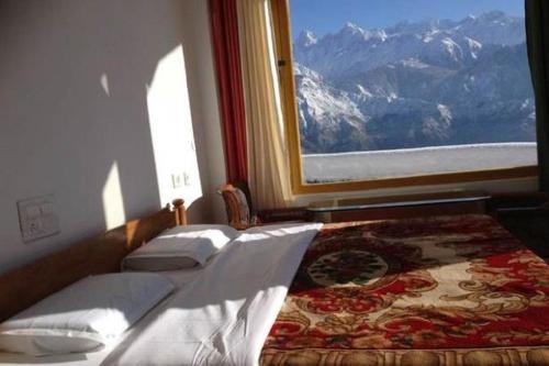 1 Schlafzimmer mit 2 Betten und einem Fenster mit Bergblick in der Unterkunft Hotel Milam Inn in Munsyari