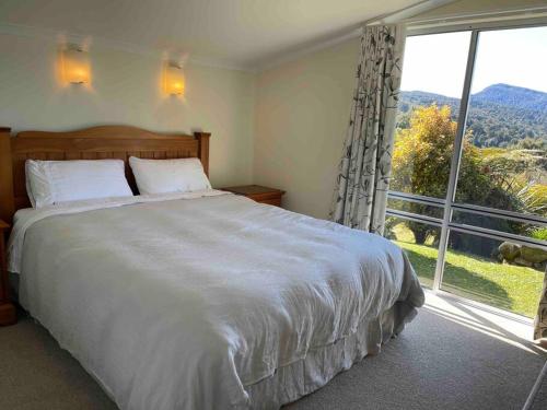 ein Schlafzimmer mit einem großen Bett und einem großen Fenster in der Unterkunft The Lake House at Waikaremoana in Tuai