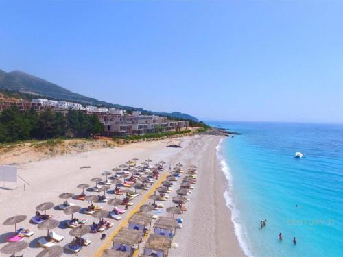 a beach with a bunch of umbrellas and the ocean at Palm Side Drymades in Dhërmi