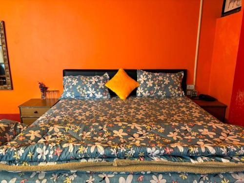 uma cama num quarto com uma parede laranja em darjeeling homestay and restuarent em Darjeeling