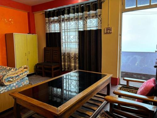 uma sala de estar com uma mesa de vidro em frente a uma janela em darjeeling homestay and restuarent em Darjeeling