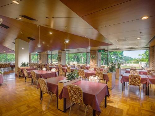 a restaurant with tables and chairs and large windows at Sennomori in Ise
