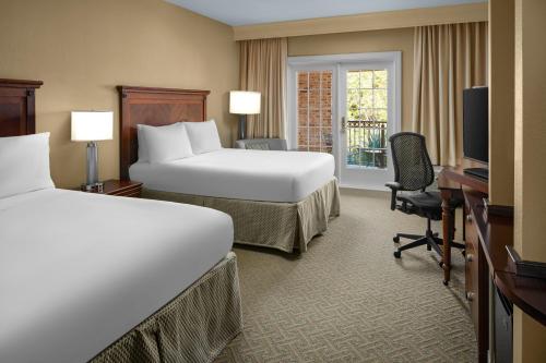 a hotel room with two beds and a desk and a television at Courtyard Charleston Mount Pleasant in Charleston